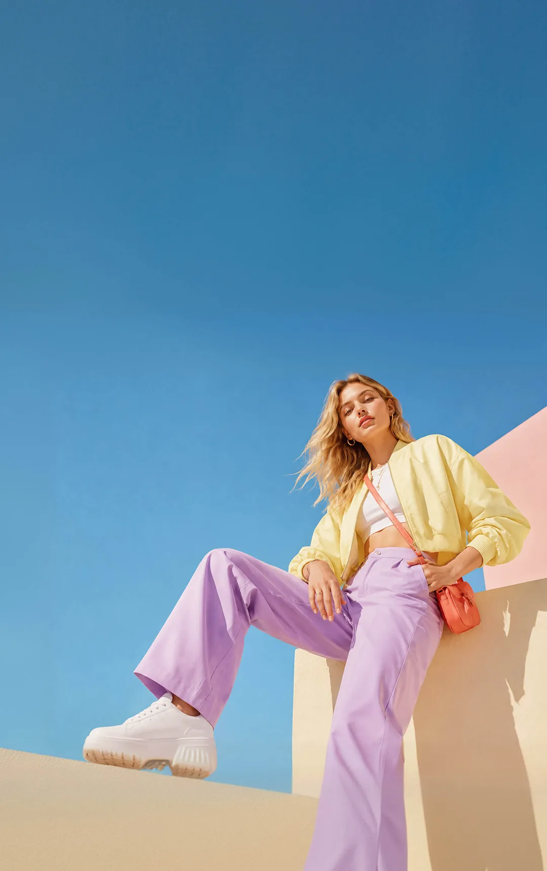 Woman in a yellow jacket and lilac trousers against a blue sky, representing colour-season styling